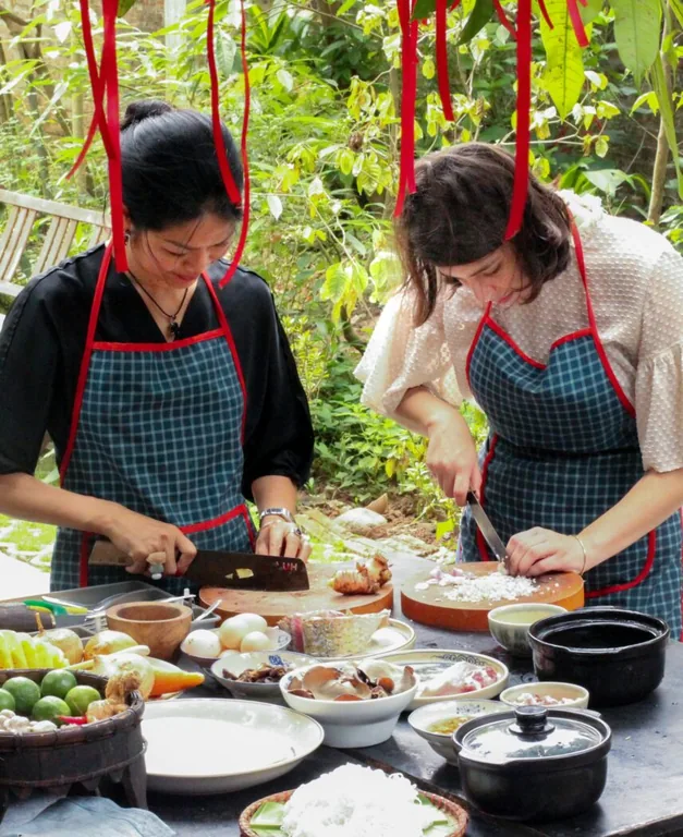 Friends in red aprons preparing dishes at an outdoor cooking class