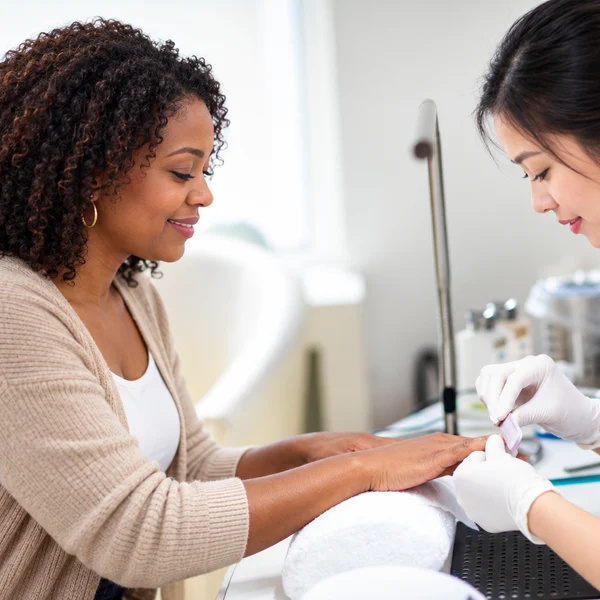 A guest smiling during a manicure in a bright, elegant salon
