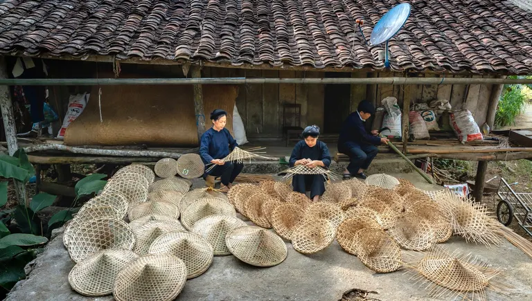 Artisans making conical hats in a countryside craft village
