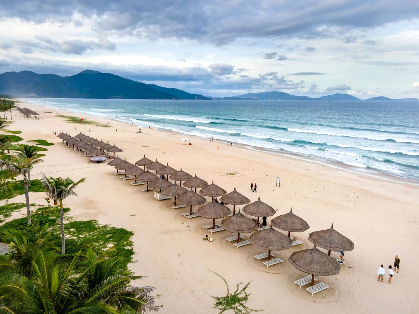 Rows of thatched beach umbrellas along the wide sandy shore of Da Nang