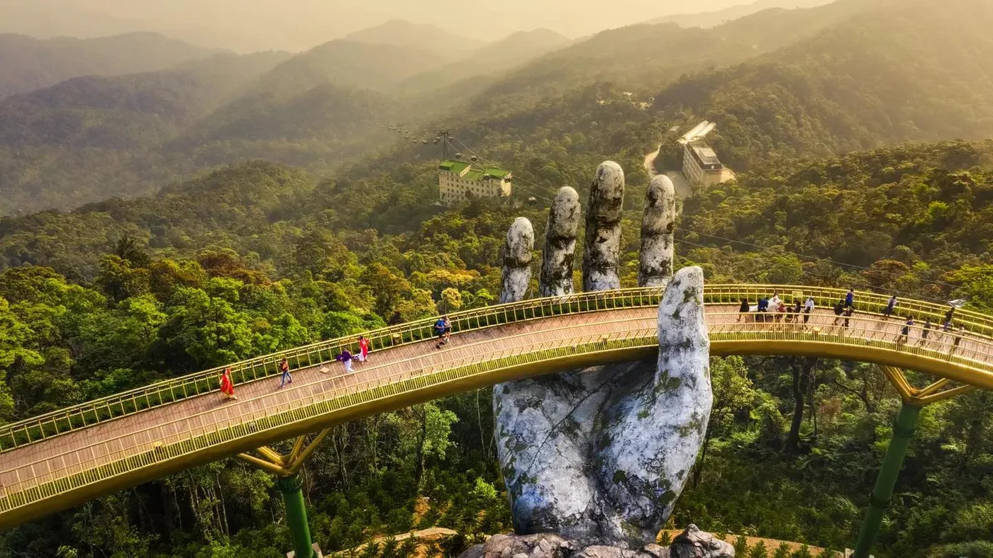 The Golden Bridge held by giant stone hands above the forested Ba Na Hills