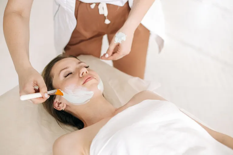 A woman relaxing as a face mask is brushed on during a facial