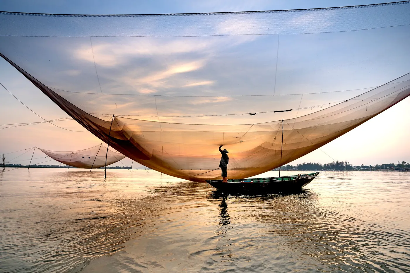 A fisherman with a lift net at sunset near Hoi An