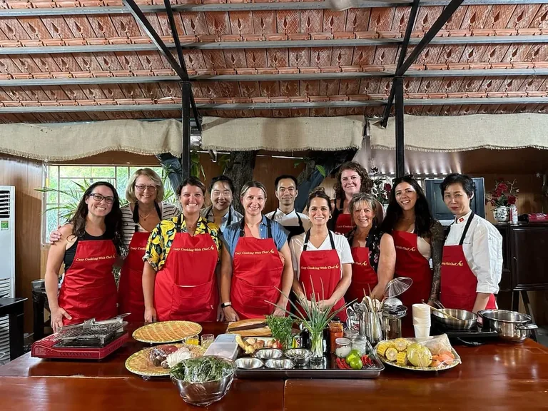 A group of travellers in aprons at a Vietnamese cooking class
