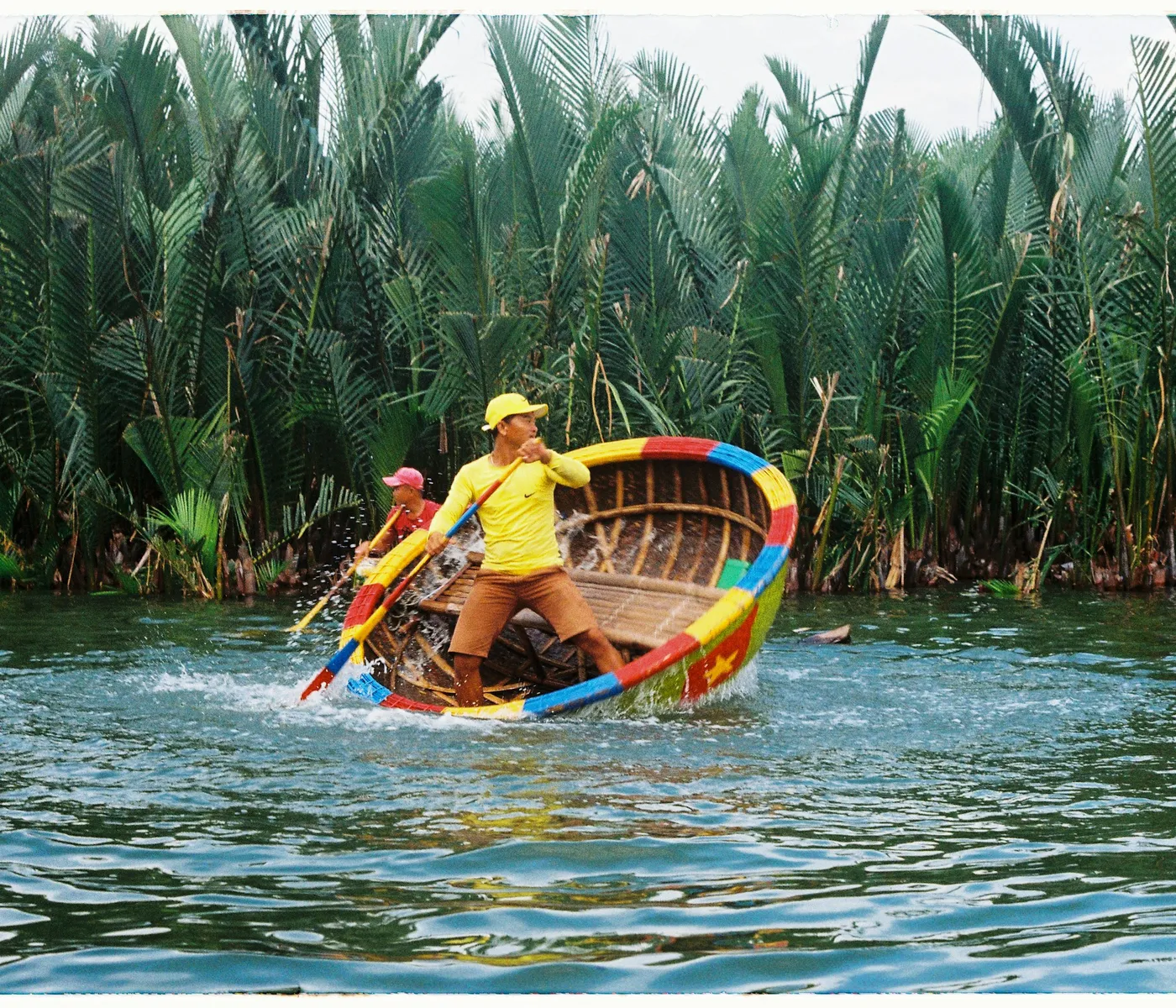 A basket boat spinning through the Cam Thanh coconut forest
