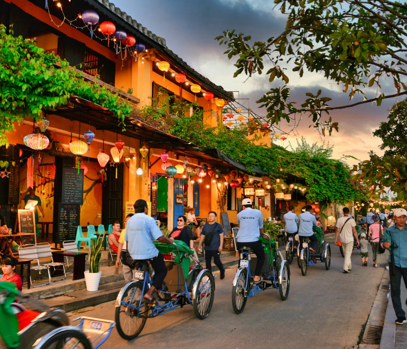 Lantern-lit cafés and cyclos on a Hoi An street at dusk