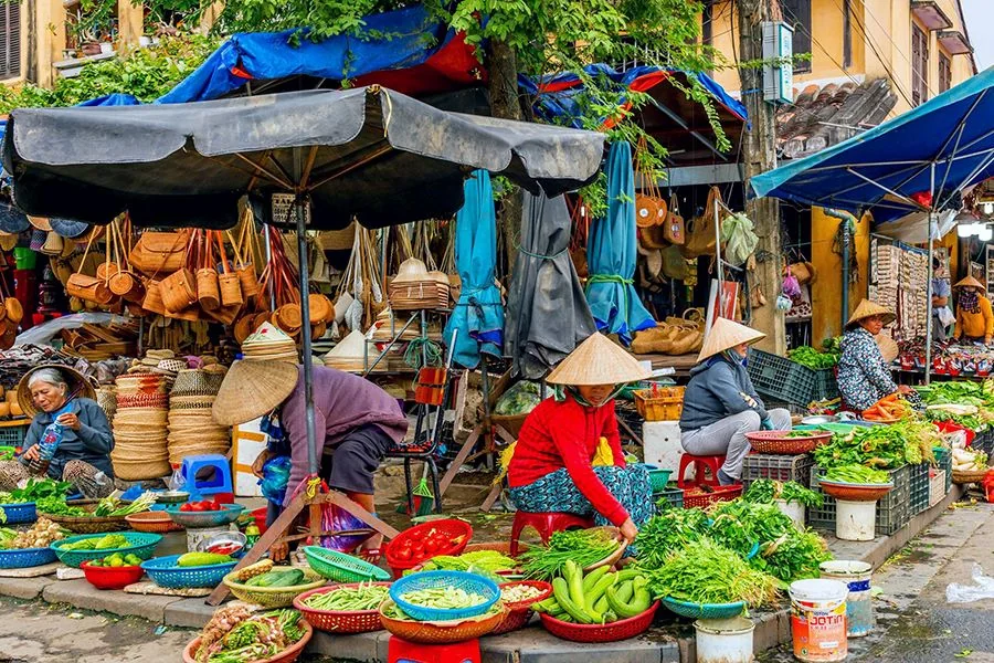 Vendors in conical hats selling fresh vegetables at a Hoi An market
