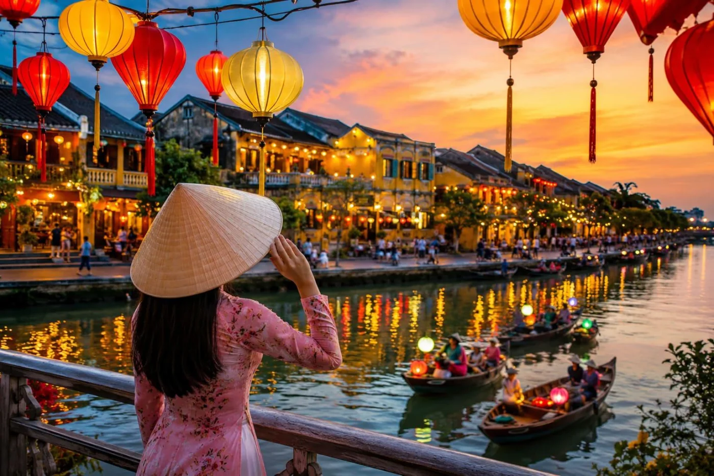 A woman in an ao dai and conical hat watching lantern boats on the Hoai River at sunset in Hoi An