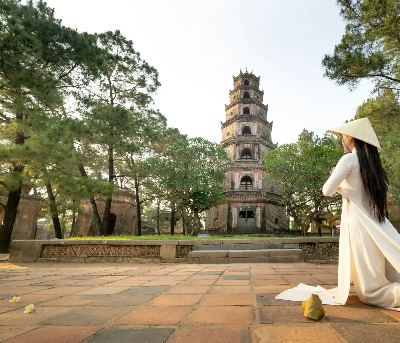 A woman in an ao dai before the tower of Thien Mu Pagoda