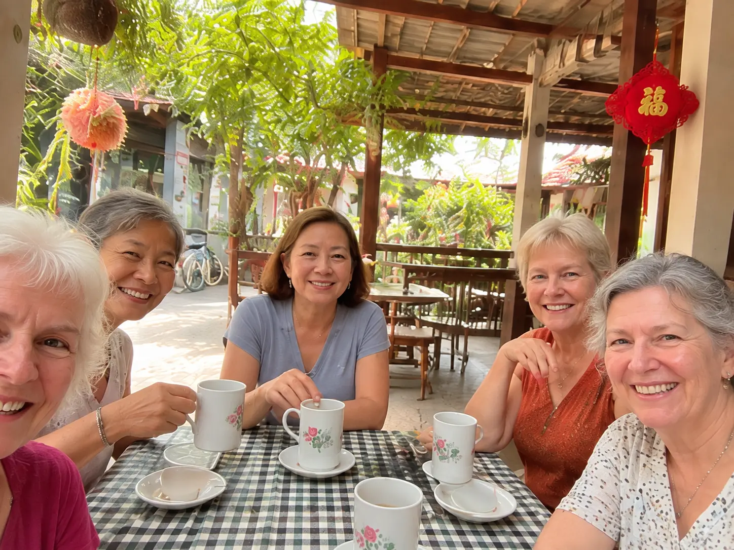 Four friends laughing over tea at a garden cafe