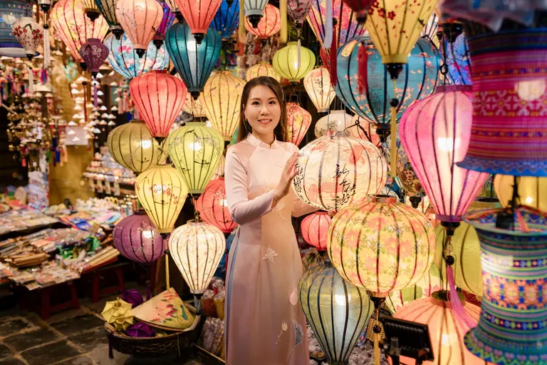 A woman in an ao dai among colourful silk lanterns in Hoi An