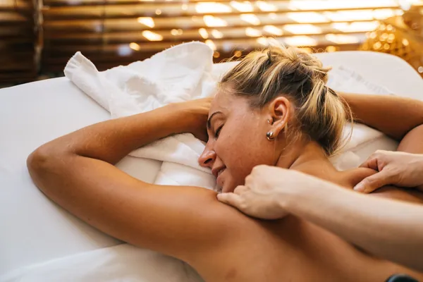 A woman relaxing during a shoulder massage in a softly lit spa