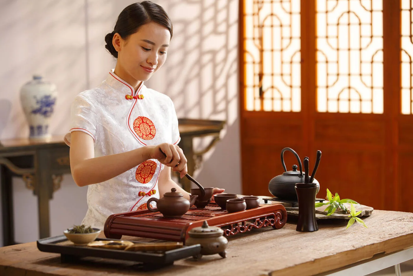 A tea host preparing tea on a carved wooden tea tray
